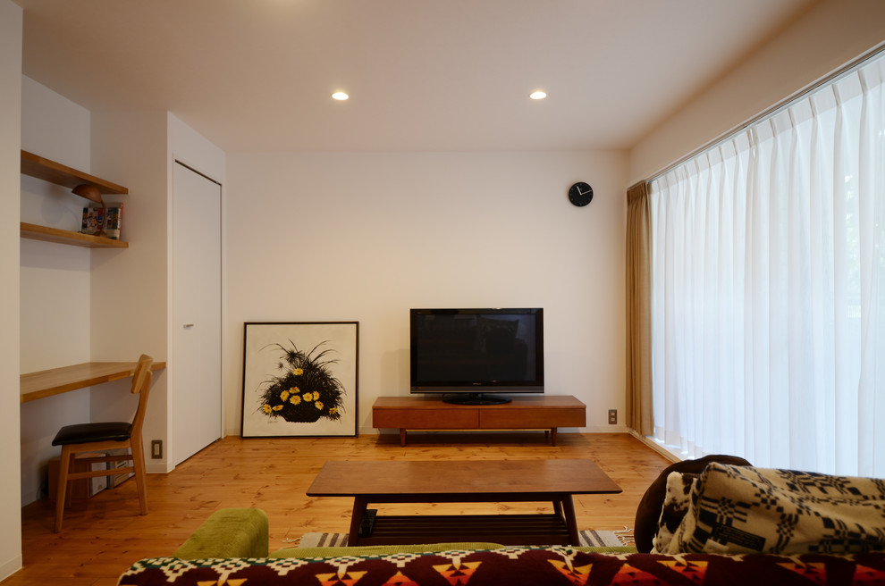 Photo of a midcentury living room in Kobe with white walls, medium hardwood flooring, a freestanding tv and brown floors.