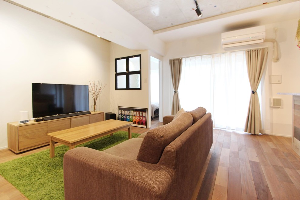 На фото: гостиная комната в скандинавском стиле с белыми стенами, паркетным полом среднего тона, отдельно стоящим телевизором и коричневым полом