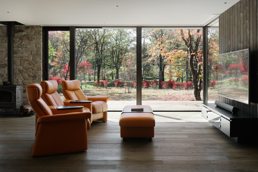 Idee per un soggiorno design aperto con pareti marroni, parquet scuro, stufa a legna, cornice del camino in pietra, TV a parete e pavimento marrone