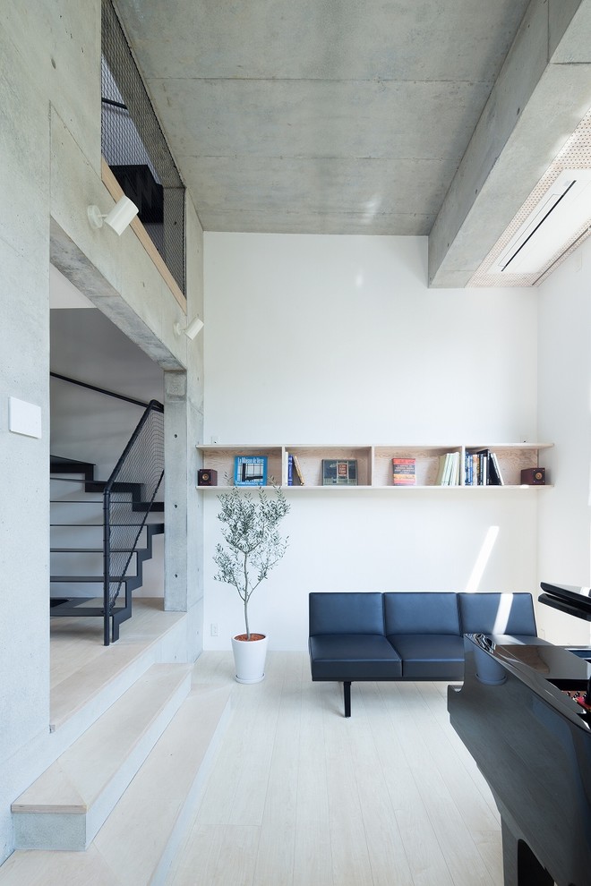 Idées déco pour un salon moderne fermé avec un mur blanc, parquet clair et canapé noir.