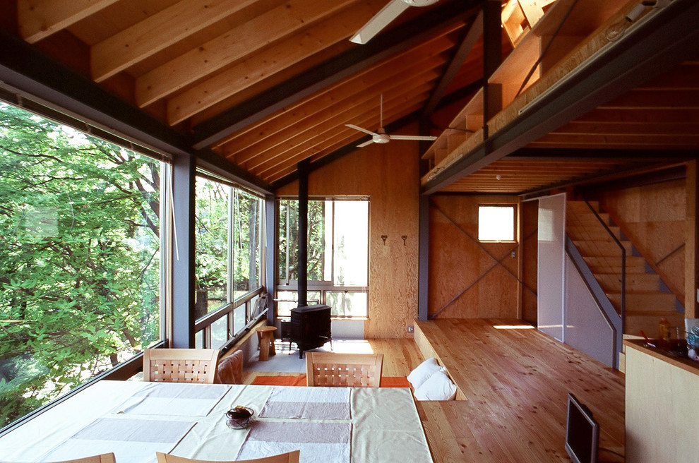Foto di un soggiorno etnico con pareti marroni, pavimento in legno massello medio, stufa a legna, cornice del camino in cemento e pavimento marrone