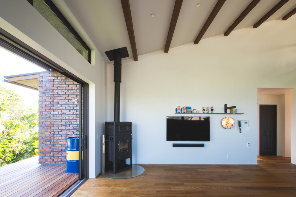 Cette photo montre un grand salon ouvert avec un mur blanc, parquet foncé, un poêle à bois, un manteau de cheminée en métal, un téléviseur fixé au mur et un sol marron.