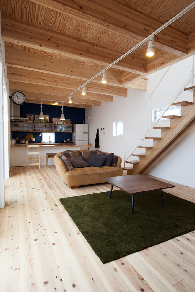 Modelo de salón abierto nórdico sin chimenea y televisor con paredes blancas y suelo de madera clara