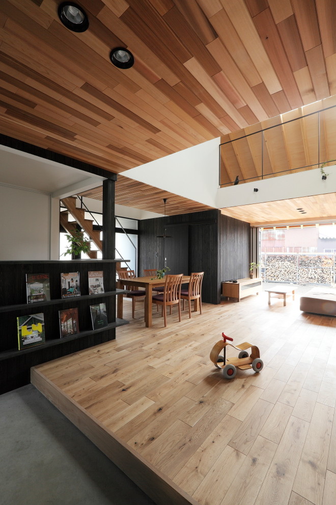 Ejemplo de salón abierto retro de tamaño medio con paredes negras, suelo de madera en tonos medios, televisor colgado en la pared y suelo beige