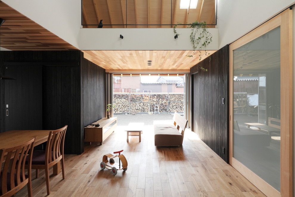 Diseño de salón abierto de estilo zen de tamaño medio con paredes negras, suelo de madera en tonos medios, televisor colgado en la pared y suelo beige