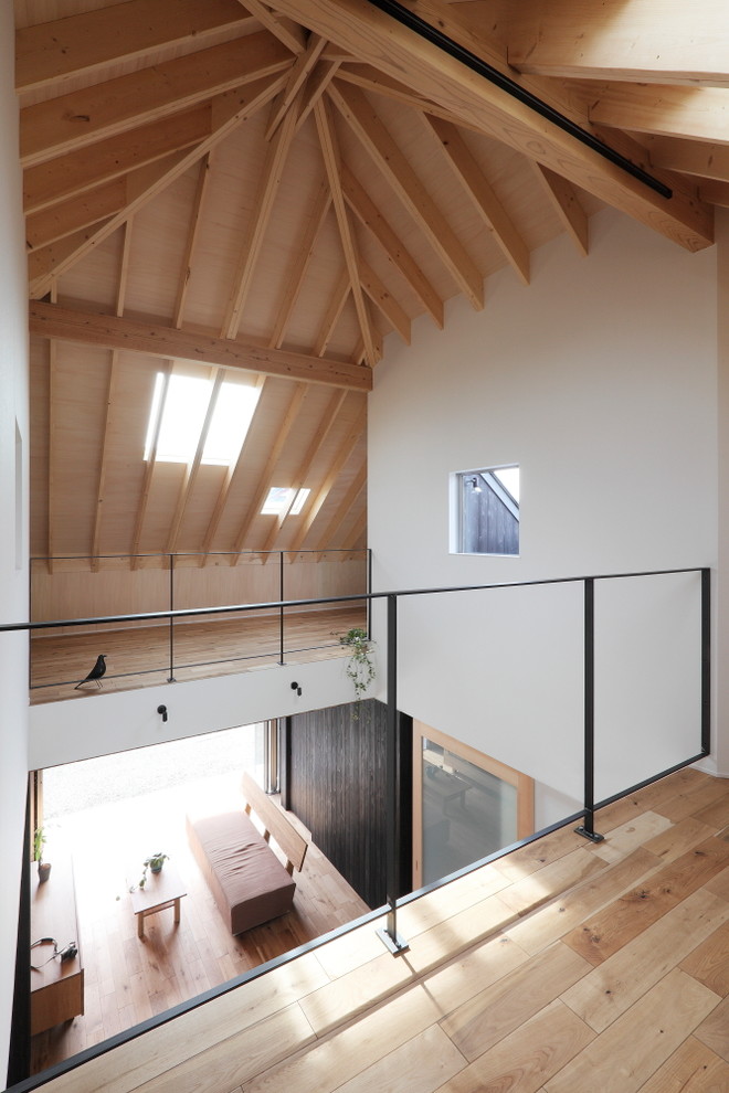 Immagine di un soggiorno minimalista di medie dimensioni e aperto con pareti nere, pavimento in legno massello medio, TV a parete e pavimento beige