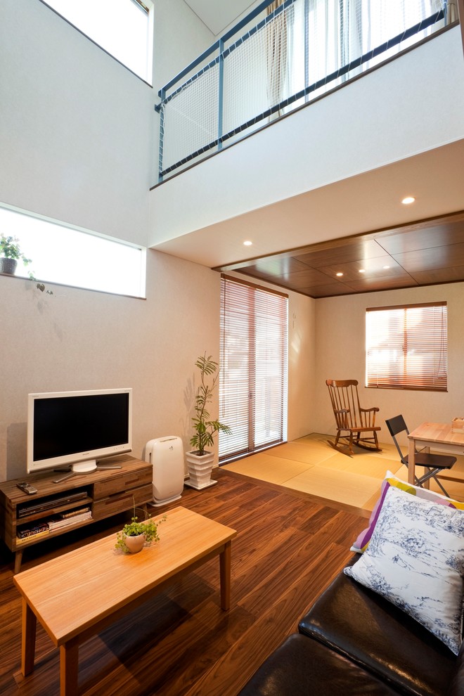 Inspiration för moderna vardagsrum, med vita väggar, mellanmörkt trägolv, en fristående TV och brunt golv