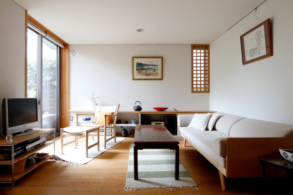 Ejemplo de salón de estilo zen con paredes blancas, suelo de madera en tonos medios, televisor independiente y suelo marrón