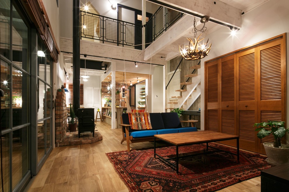 Diseño de salón urbano sin televisor con paredes blancas, suelo de madera clara, estufa de leña y marco de chimenea de ladrillo
