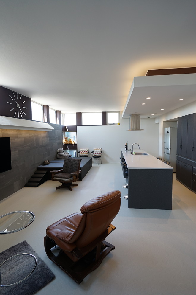 На фото: маленькая открытая гостиная комната в стиле модернизм с разноцветными стенами, телевизором на стене и серым полом для на участке и в саду