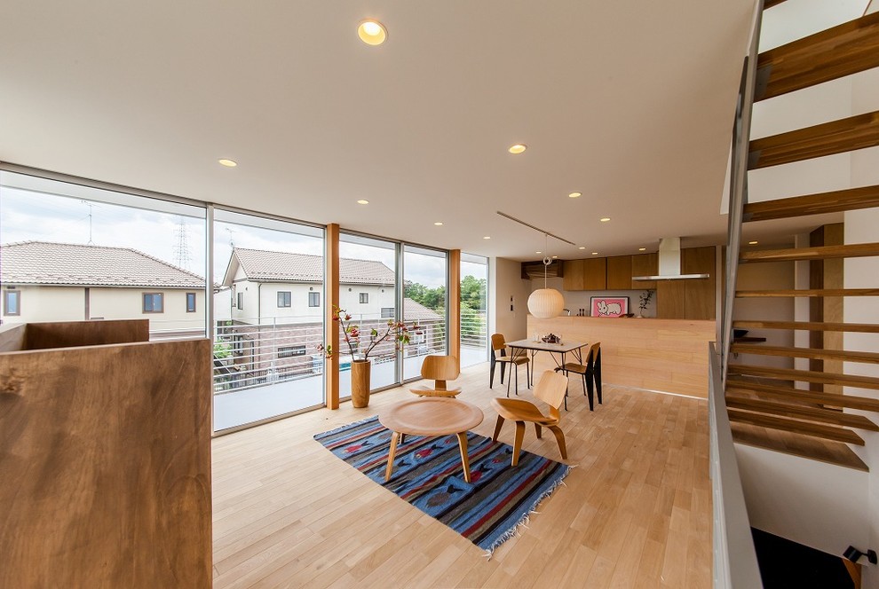 Mittelgroßes, Offenes Modernes Wohnzimmer mit weißer Wandfarbe, hellem Holzboden, freistehendem TV und beigem Boden in Sonstige