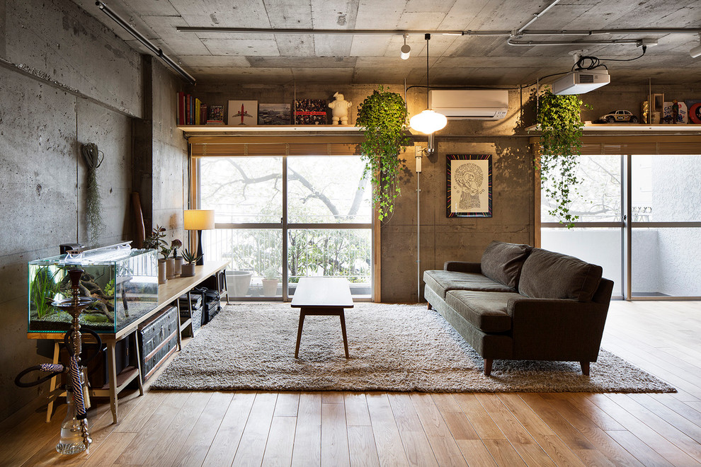 Esempio di un soggiorno industriale con pareti grigie, pavimento in legno massello medio e nessun camino
