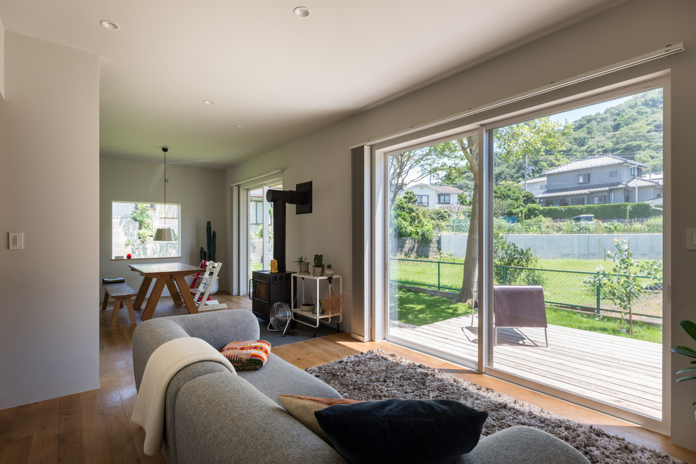 Immagine di un soggiorno minimal con pareti bianche, pavimento in legno massello medio e pavimento marrone