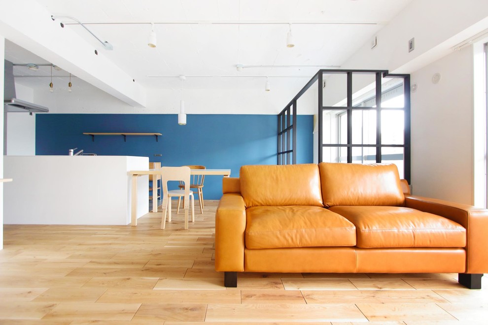 Diseño de salón abierto rural con paredes azules, suelo de madera clara y suelo beige
