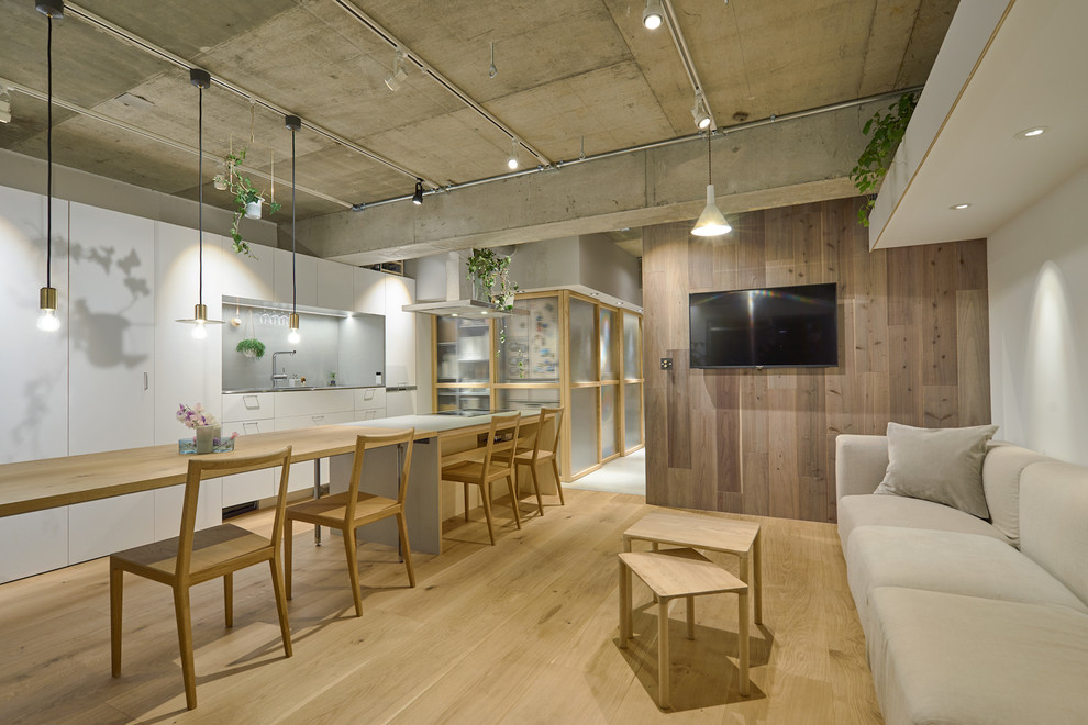 Diseño de salón abierto asiático con paredes blancas, suelo de madera clara, televisor colgado en la pared y suelo marrón