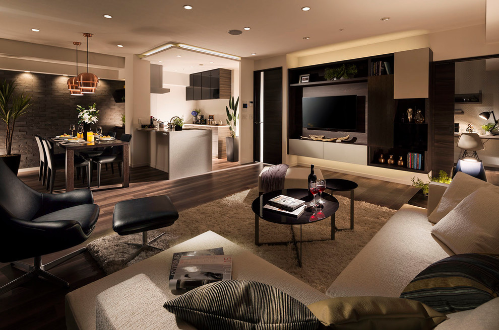На фото: гостиная комната в современном стиле с разноцветными стенами, паркетным полом среднего тона, телевизором на стене и коричневым полом
