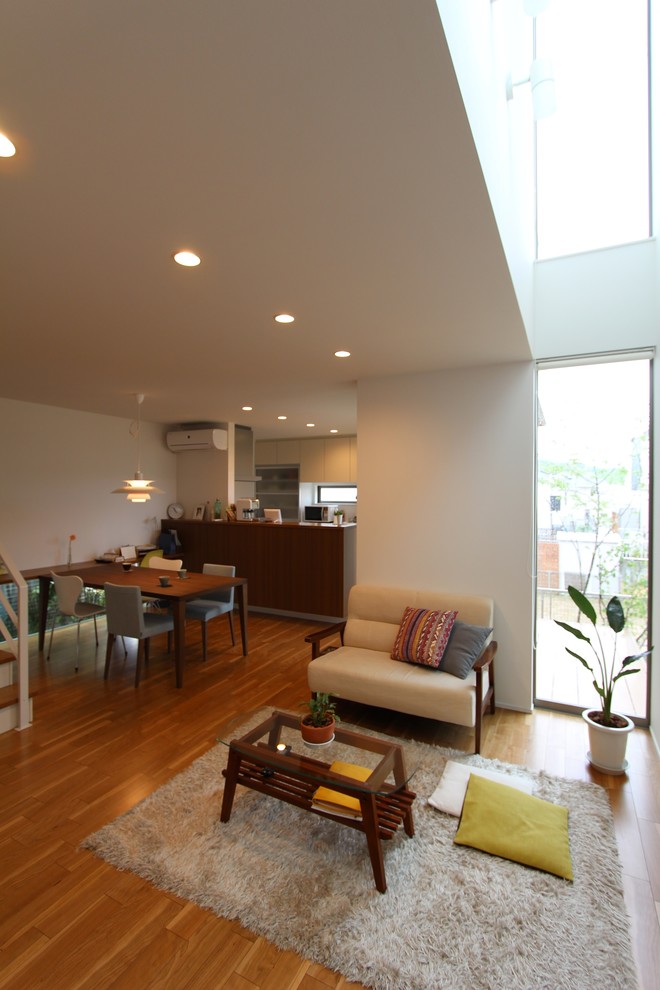 Modelo de salón abierto minimalista pequeño sin chimenea con paredes blancas, suelo de contrachapado, televisor independiente y suelo beige