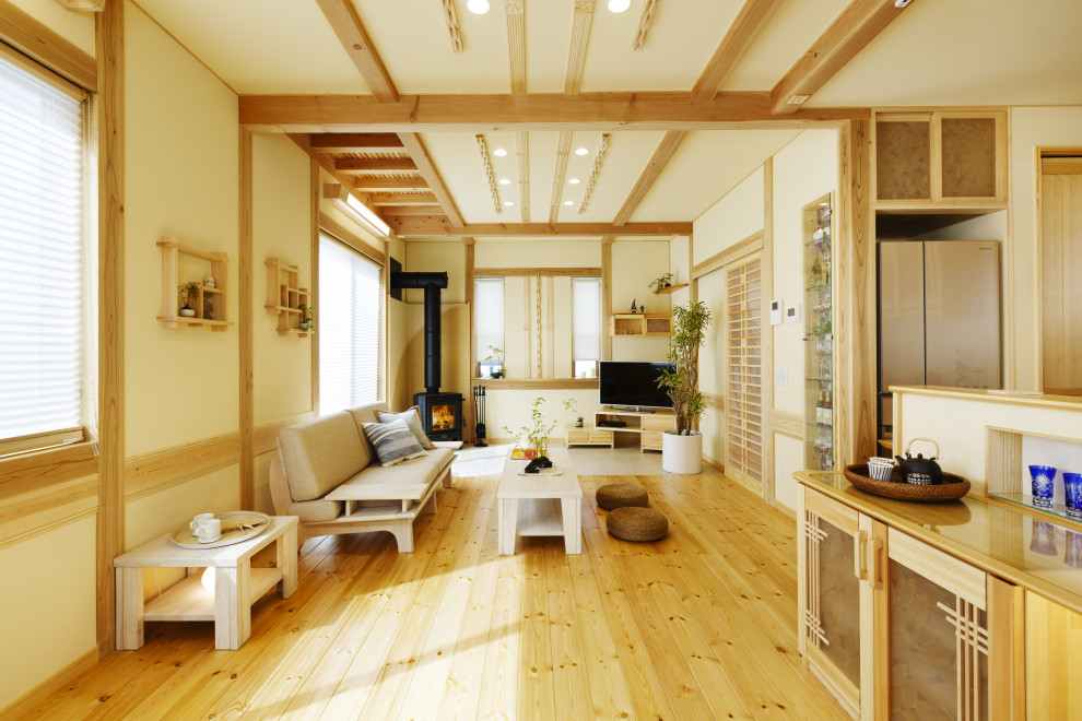 Exemple d'un salon asiatique ouvert avec un mur blanc, parquet clair, un poêle à bois, un téléviseur d'angle, un sol beige et poutres apparentes.