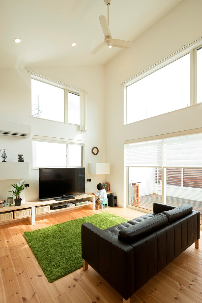 Ejemplo de salón abierto contemporáneo con paredes blancas, suelo de madera en tonos medios, televisor independiente, suelo marrón y alfombra