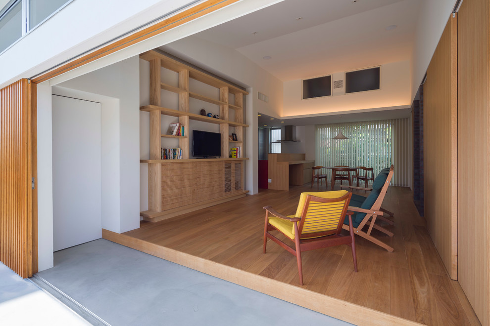 Стильный дизайн: гостиная комната в восточном стиле с белыми стенами, паркетным полом среднего тона и отдельно стоящим телевизором - последний тренд