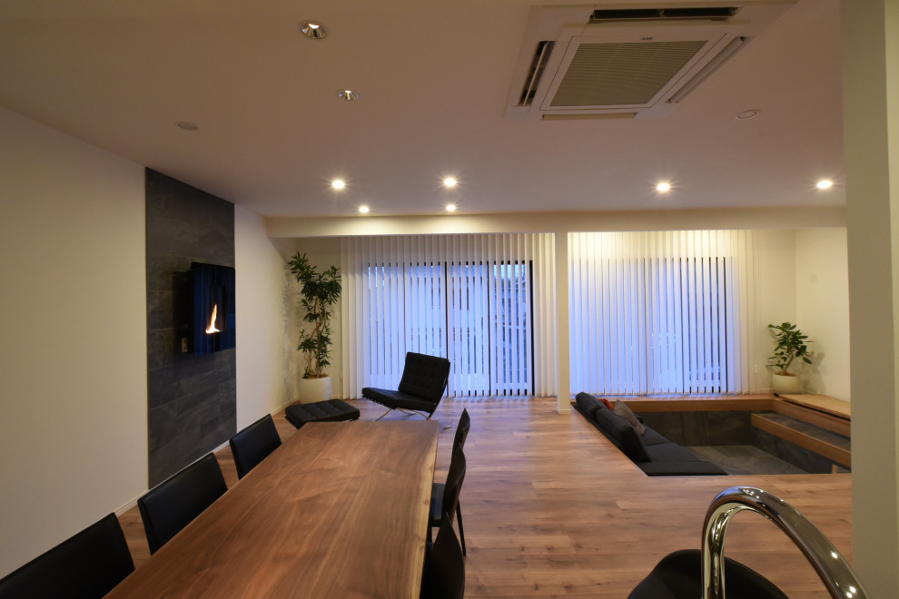 Großes Modernes Wohnzimmer mit weißer Wandfarbe, Sperrholzboden, gefliester Kaminumrandung und braunem Boden in Kobe