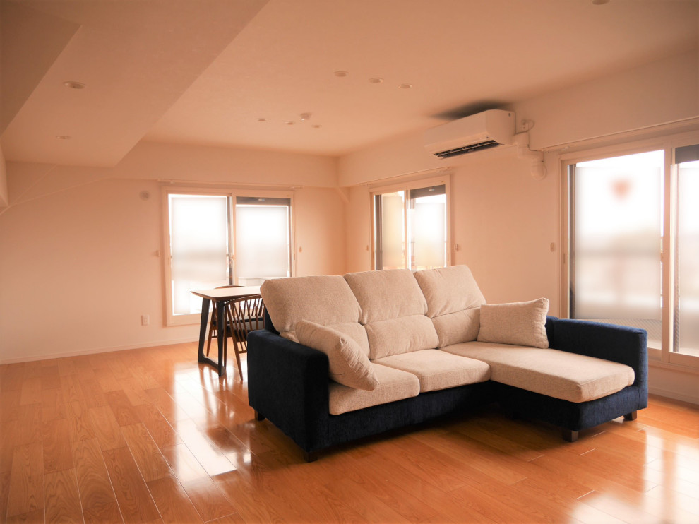 Imagen de salón abierto de tamaño medio con paredes blancas, suelo de contrachapado, suelo marrón, papel pintado y papel pintado