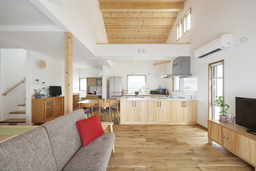 Cette image montre un salon rustique ouvert avec un mur blanc, un sol en bois brun, aucune cheminée, un sol marron et un téléviseur indépendant.