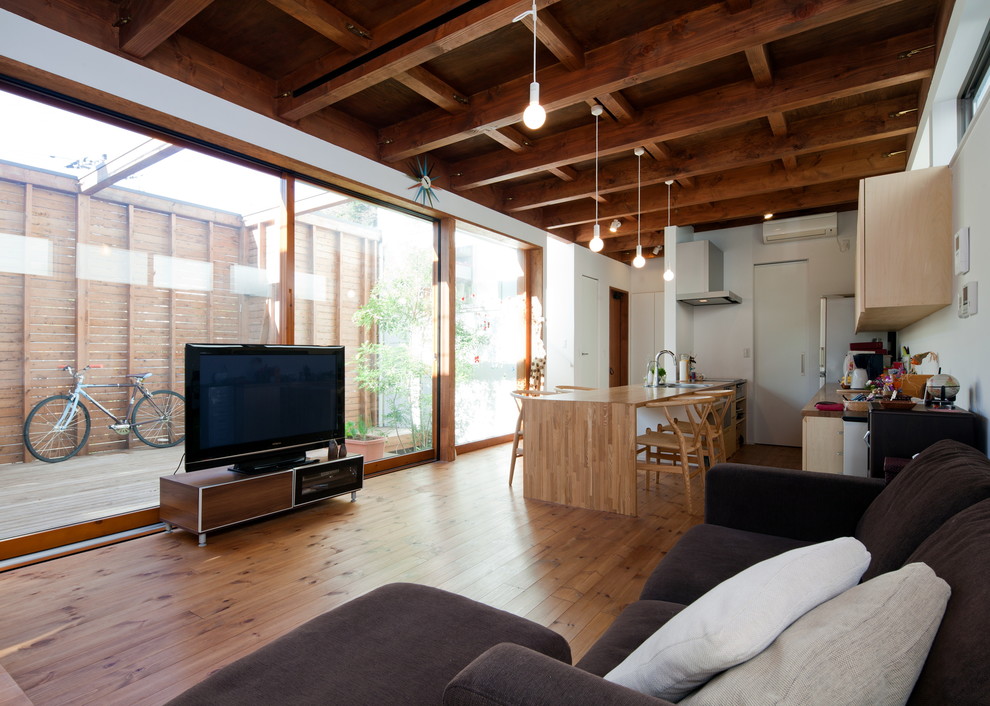 Ispirazione per un soggiorno design con pareti bianche, pavimento in legno massello medio, nessun camino, TV autoportante e pavimento marrone