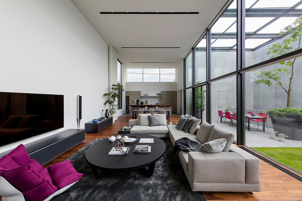 Cette photo montre un salon moderne avec un mur blanc, un sol en bois brun, un téléviseur indépendant et un sol marron.