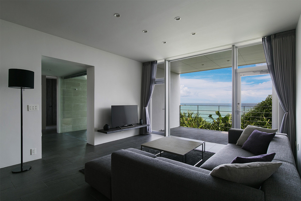Immagine di un soggiorno minimalista con pareti bianche, TV autoportante e pavimento grigio