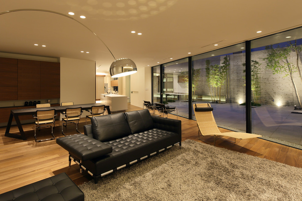 Imagen de salón abierto moderno con paredes beige, suelo de madera en tonos medios y suelo marrón