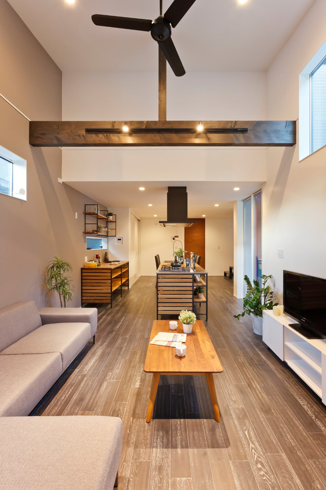 На фото: открытая гостиная комната в стиле модернизм с разноцветными стенами, деревянным полом и серым полом с