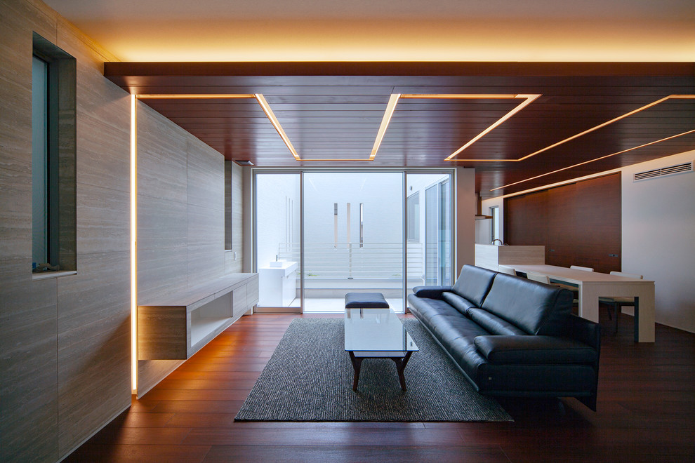 Cette image montre un salon minimaliste ouvert avec un mur multicolore, un sol en bois brun, un sol marron et canapé noir.