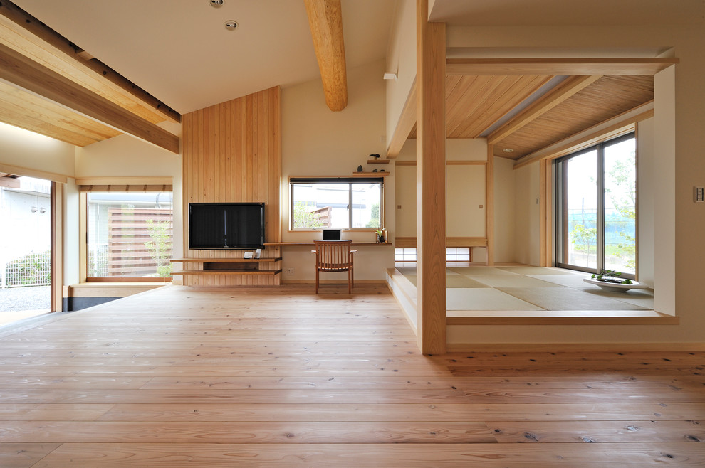 Ejemplo de salón de estilo zen con paredes beige, suelo de madera clara, televisor colgado en la pared y suelo beige