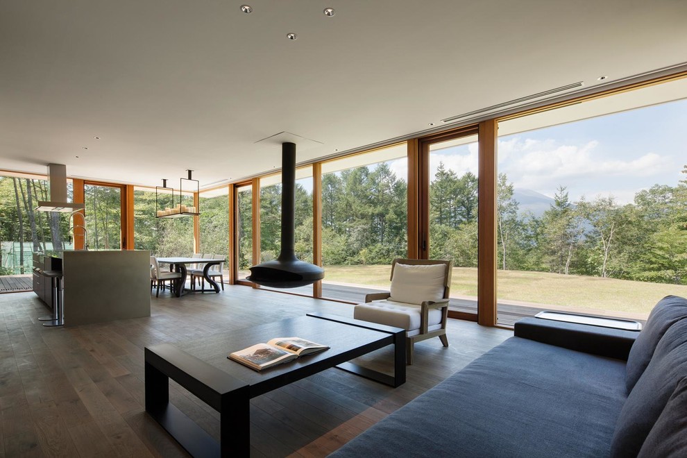 Ispirazione per un soggiorno minimalista aperto con pavimento in legno massello medio, camino sospeso e nessuna TV