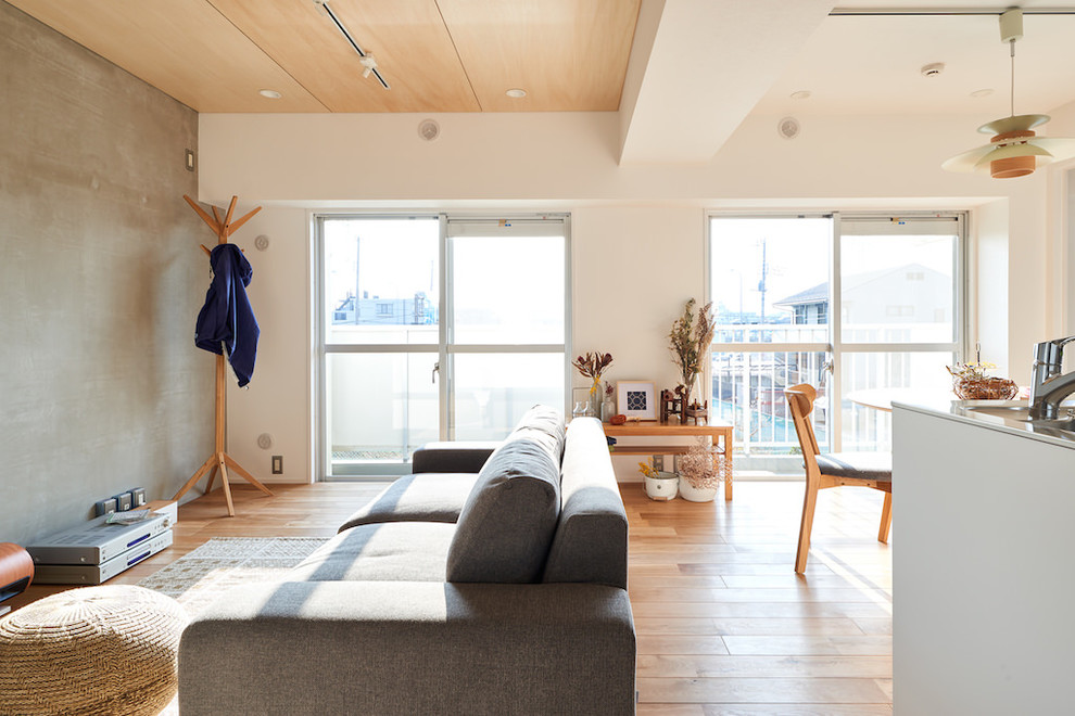 Esempio di un soggiorno design aperto con pareti grigie, pavimento beige e parquet chiaro