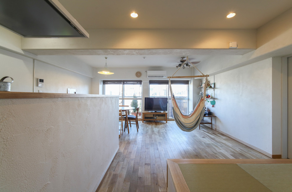 Photo of a scandi open plan living room in Tokyo with white walls, medium hardwood flooring, no fireplace, brown floors and a freestanding tv.
