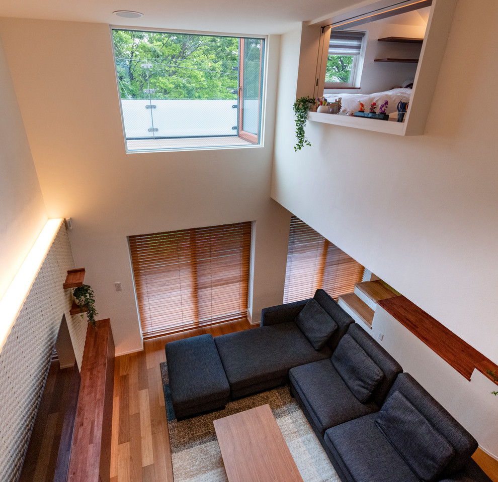 Inspiration pour un salon minimaliste de taille moyenne avec un mur blanc, un sol en bois brun, aucune cheminée, un téléviseur fixé au mur et un sol marron.