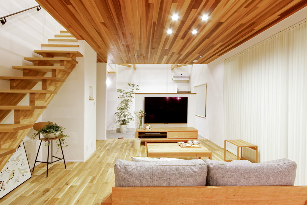 Aménagement d'un salon asiatique ouvert avec un mur blanc, parquet clair, cheminée suspendue, un manteau de cheminée en béton, un téléviseur indépendant et un sol marron.