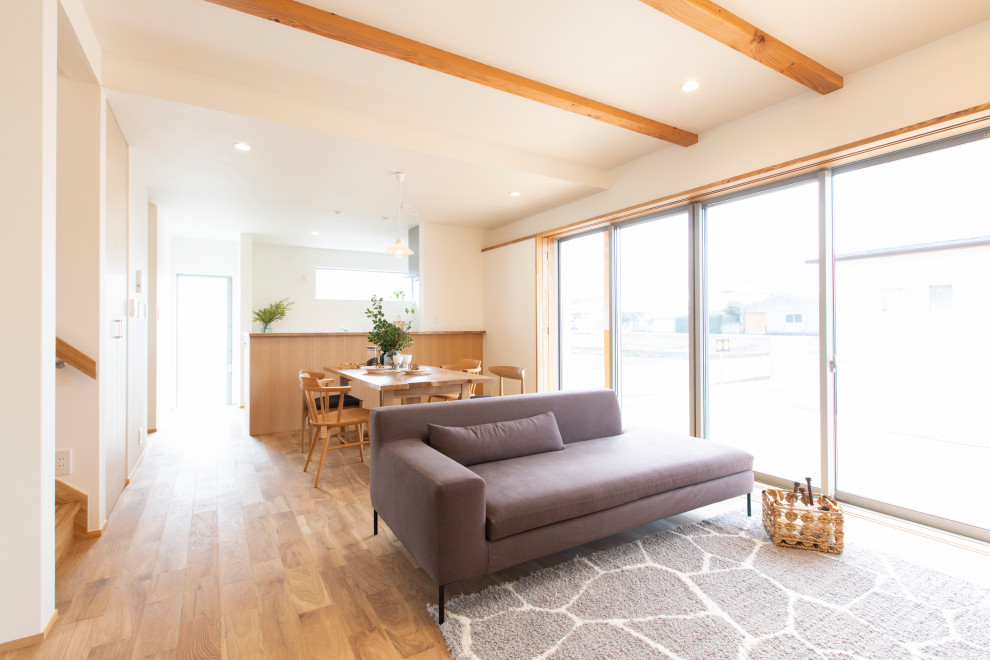 Offenes Asiatisches Wohnzimmer ohne Kamin mit braunem Holzboden und Tapetendecke in Sonstige