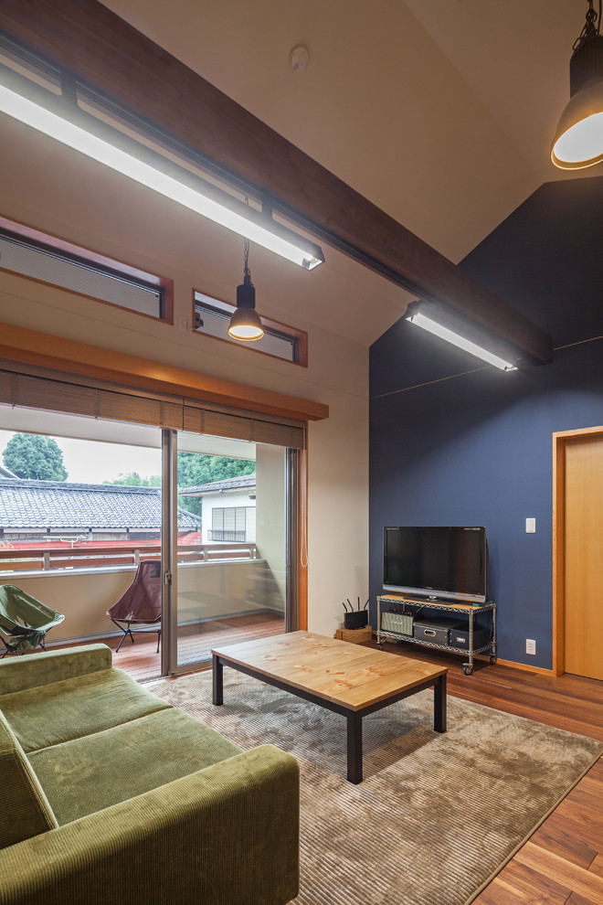 Aménagement d'un salon asiatique avec un mur multicolore, un sol en bois brun, un téléviseur indépendant et un sol marron.