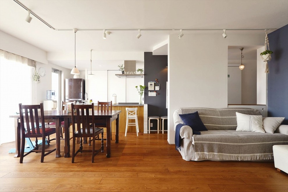 Offenes Landhausstil Wohnzimmer mit weißer Wandfarbe, braunem Holzboden und braunem Boden