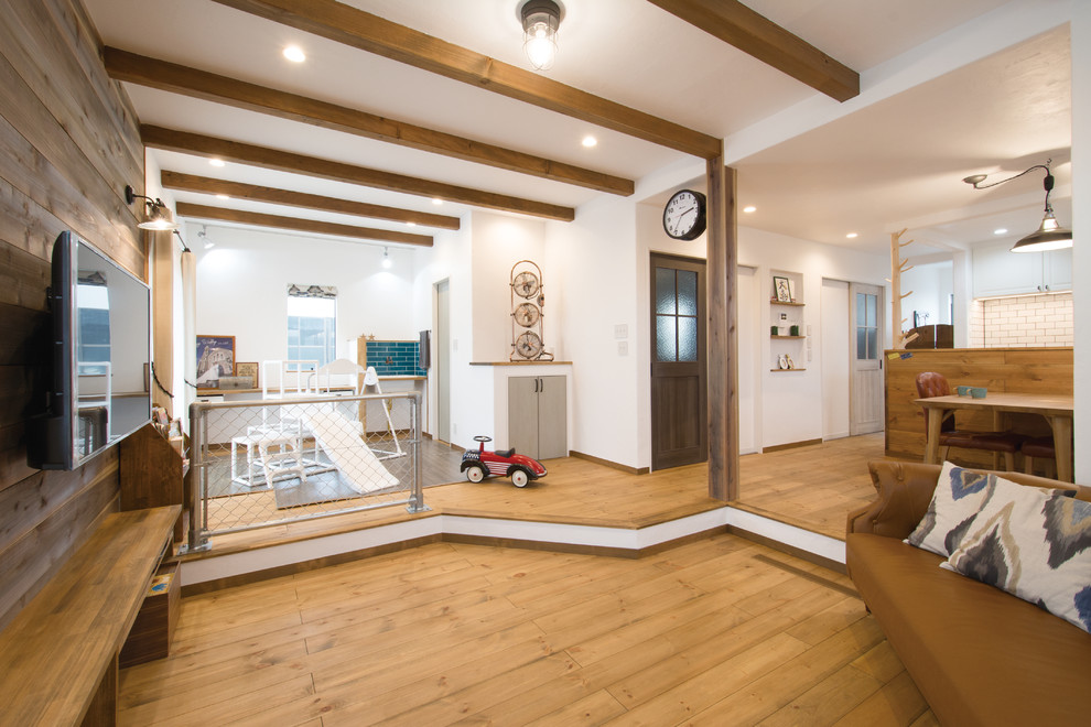 Modelo de salón abierto clásico sin chimenea con paredes blancas, suelo de madera clara, televisor colgado en la pared y suelo marrón