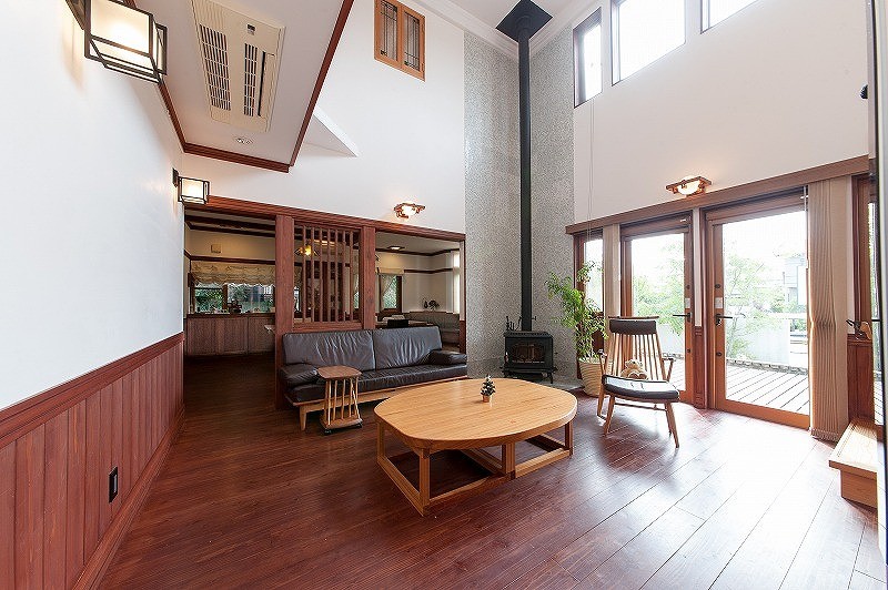 Großes, Abgetrenntes Modernes Wohnzimmer mit weißer Wandfarbe, dunklem Holzboden, Kaminofen, gefliester Kaminumrandung, TV-Wand und schwarzem Boden in Nagoya