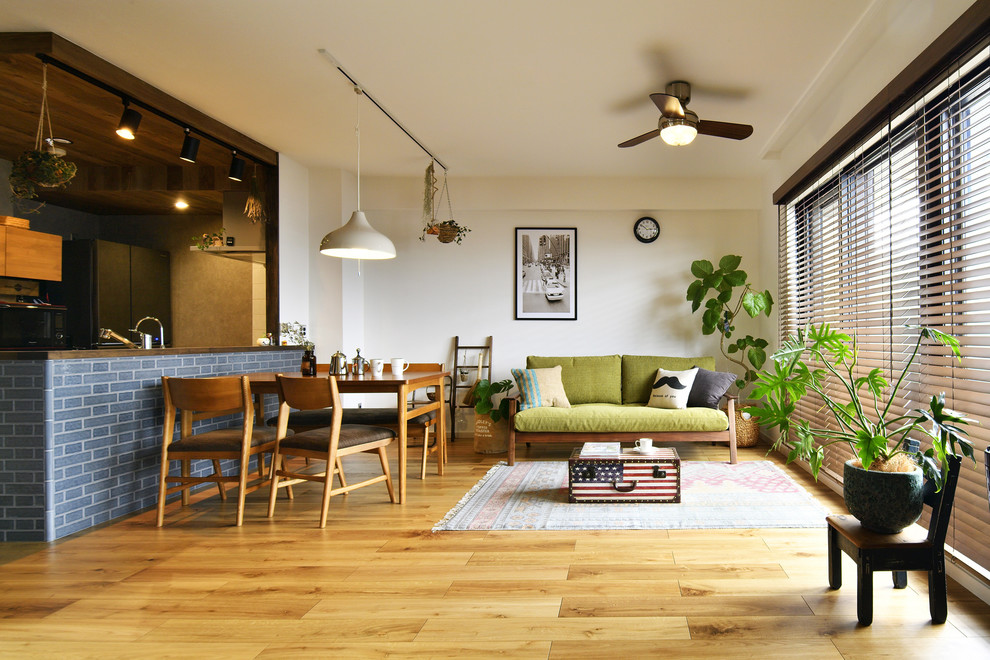 Offenes Skandinavisches Wohnzimmer mit weißer Wandfarbe, braunem Holzboden und braunem Boden in Sonstige