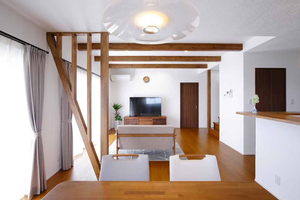 На фото: гостиная комната в восточном стиле с белыми стенами, паркетным полом среднего тона и коричневым полом с