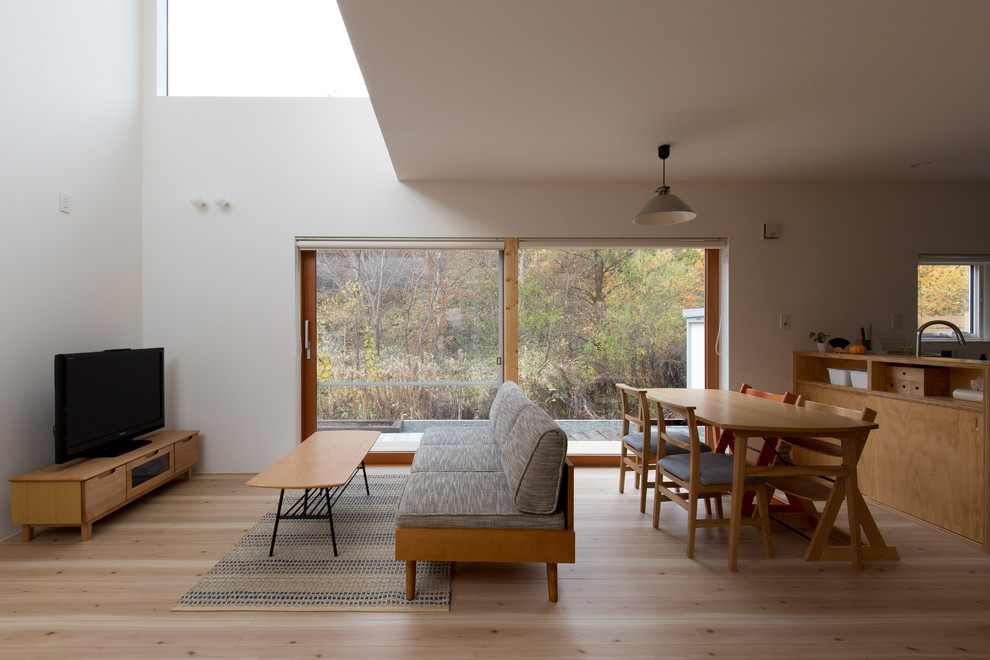 Идея дизайна: открытая гостиная комната в скандинавском стиле с белыми стенами, светлым паркетным полом, отдельно стоящим телевизором и бежевым полом