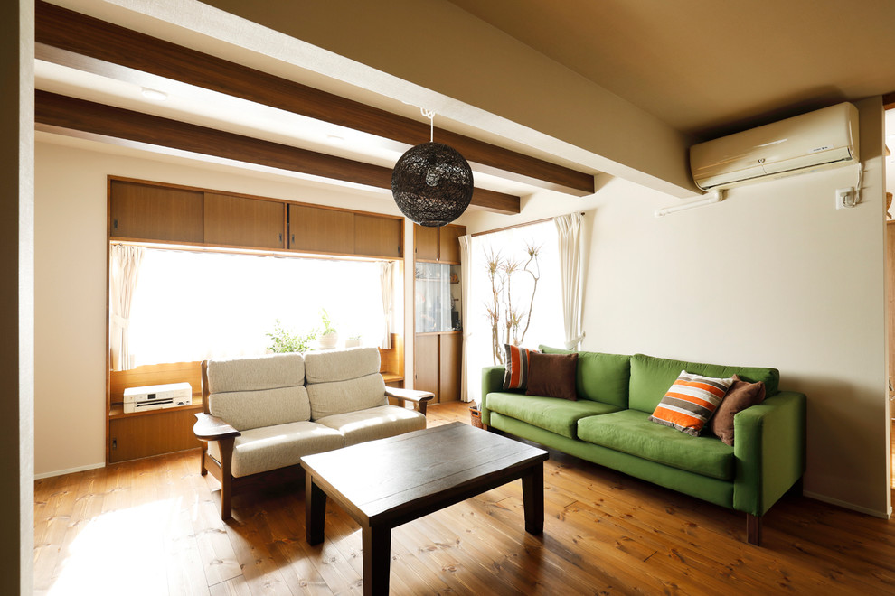 Inspiration pour un salon design ouvert avec un mur beige, un sol en bois brun, un téléviseur indépendant et un sol marron.