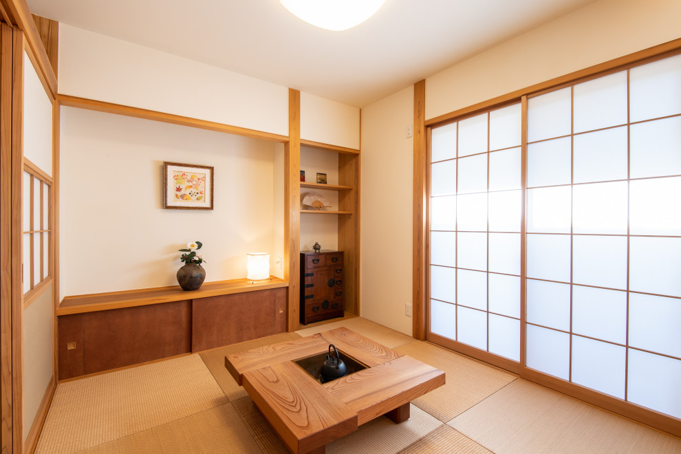 Aménagement d'un salon asiatique de taille moyenne et ouvert avec un mur blanc, un sol de tatami, un poêle à bois, un manteau de cheminée en pierre, aucun téléviseur et un sol beige.