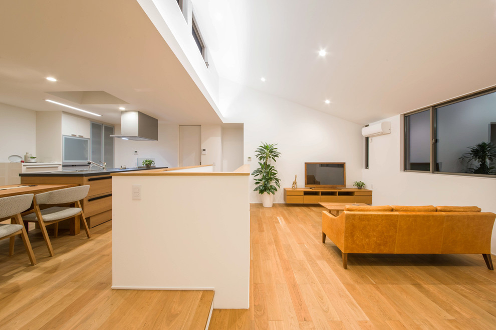 Idee per un soggiorno moderno aperto con pareti bianche, pavimento in compensato, TV autoportante e pavimento marrone